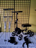 Photo showing Elenker knee scooter, aluminum crutches, and two knee braces