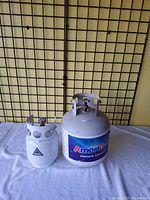 Front view of two propane tanks side by side, smaller white 8.8-pound tank and larger AmeriGas labeled 15-pound tank.