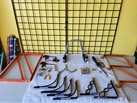 Overview of all items in lot including wall shelving brackets, hand air pump, clamps, and hooks.