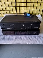 Front view of Magnavox VHS/DVD combo player sitting on top of OPPO BDP-83 Blu-ray player, showing front controls and disc slots.