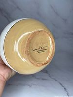 View of the bottom of the pottery vase with Diana Fayt signature and maker mark 'Synergy Designs Hand Decorated'