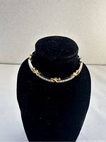 Full view of the gold and silver toned bracelet displayed on black velvet display stand, shows overall design and two-tone style.