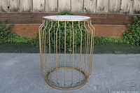 Full side view of the entire side table showing design and proportion next to a wooden fence and ground.