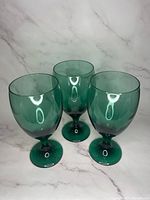 Three juniper green water goblets arranged in a triangle showing the front and side profiles.