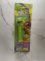 Front of original sealed packaging showing green Kermit The Frog PEZ candy dispenser and candy.