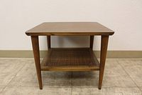 Full front view of the Mid Century wooden side table showing the rectangular top and cane bottom shelf with four tapered legs.