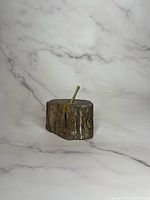 Side view of the vintage petrified wood paperweight with brass stick, showing textured wood sides and smooth top.
