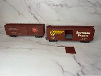 Three brown HO scale model train boxcars on display, one with removable sliding door shown removed.