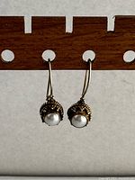 Front view of vintage sterling silver earrings with round white pearls set in decorative silver.