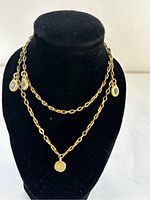 Front view of vintage double chain gold plated necklace with coin and oval charms displayed on black stand