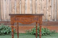Front view of Victorian oak side table showing carved apron with floral scroll design and top surface.