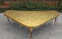 View of the gold triangular coffee table showing ornate carved floral details and patina on the gold finish