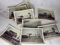 Photo showing a spread of black and white vintage locomotive photos, mostly side profiles of steam engines with tall smoke stacks.