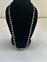 Full-length front view of vintage rhinestone necklace displayed on black stand showing entire length and sparkle of stones.