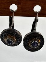Close-up photo of one vintage sterling silver earring showing blue center stone and amber stones surrounded by engraved silver design
