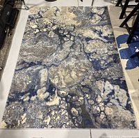 Full view of the rectangular area rug laid out on a grey floor, showing the complete pattern and size.