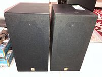 Front view of both speakers side by side showing grills and logo badges