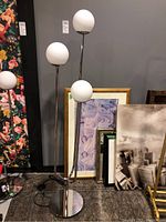 Full view of the chrome floor lamp with three white spherical shades on different height stands