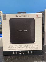 Front side of the boxed Harman Kardon Esquire wireless speaker showing the product image and description indicating it's an executive portable wireless speaker and conferencing system.