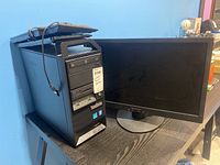 Full view of the Lenovo ThinkStation desktop computer tower with two keyboards on top and 23-inch Lenovo monitor next to it on black table.
