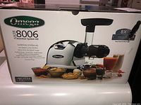 Front of sealed box showing model number, branding and promotional juice images