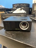 Close front angle view of the Optoma LED projector showing the lens and vent