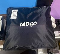 Closed LEDGO-branded black carry bag, top view