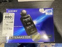 Front of original box showing Sekonic brand, LITEMASTER Pro L-478D smart light meter graphics, MaxSold inventory label “880” and price sticker $459.99