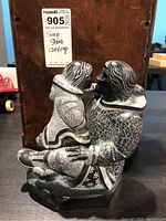 Side view of soapstone carving showing mother and child in traditional clothing with detailed etched patterns.