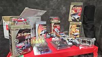 Overview of the lot with boxed Zip Zaps cars, extra car bodies, a black pouch, a performance driving kit, and a soldier figure laid out on a red table.