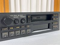 Close-up of front panel showing brand Jeep, cassette slot, Dolby system and control buttons including power, FM, AM, balance, treble, bass, and presets.