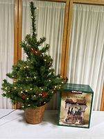Full view of the 36-inch pre-lit Christmas tree with warm white lights and red bows, standing next to the green boxed Kirkland Water Globe.