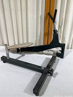 Side view of a black metal shooting rest with a wide base and an adjustable platform/tray.