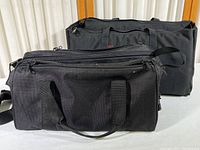 Two black canvas specialty carrying cases positioned side by side showing size difference and handles