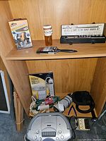 Photo of assorted items on wooden shelves including Westward socket set in metal case, pill bottle, paintbrush, and small keys.