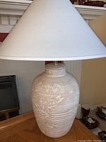 Cream ceramic table lamp with white shade on oak side table, showing full lamp and base