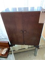 Closed wooden cabinet with dark stain and carved door details