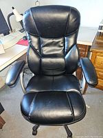 Front view of black padded office chair with cushioned seat, back and armrests showing condition