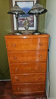 Small wooden dresser with five drawers and two metal lamps on top