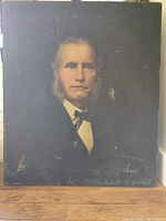 Full view of antique portrait painting depicting a man with mutton chop sideburns in a suit and bow tie on dark background.