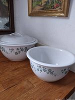 Photo showing two white Corelle stoneware bowls with green ivy leaf floral pattern on wooden surface.