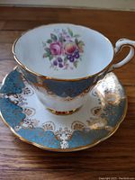 Teacup showing floral bouquet inside with gold and turquoise detailed exterior