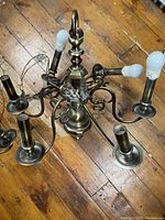 Top view of one brass chandelier showing five light bulbs, ornate scrolling arms, and hanging ring