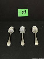Three silver teaspoons laid side by side, showing general size and shape.
