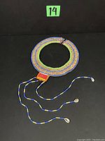 Full view of the Masai tribal beaded collar necklace laid flat showing colors and hanging cowrie shells