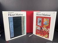 Two volumes of Henri Matisse by Aragon with dust jackets, standing open and showing front covers with illustration.