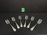 Six dessert forks laid flat in a row