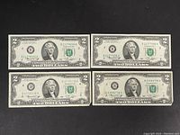Four 1976 United States $2 banknotes laid out side by side including serial numbers and visible wear