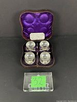 Set of four Victorian silver plated salts on ball feet with matching spoons displayed inside original purple silk-lined box.