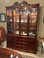 Full view of the china hutch against wall showing upper glass cabinets with interior lights, shelves with decorative plates, drawers and lower cabinets.